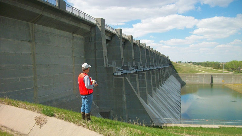 Man gazing at dam under a beautiful blue sky with few clouds